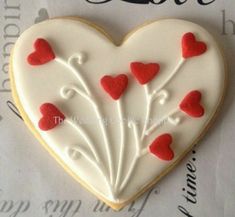 a heart shaped cookie decorated with red and white icing on top of a piece of paper