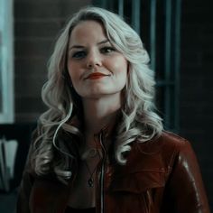 a woman with blonde hair wearing a brown leather jacket