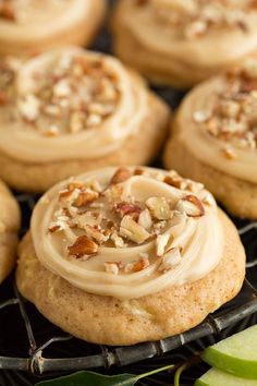 several cookies with frosting and nuts on a cooling rack