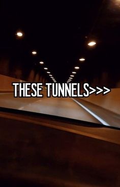 there is a car driving down the road in the dark with words that read these tunnels