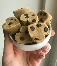 a person holding a bowl filled with chocolate chip cookies