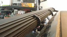 the back end of a vehicle with metal slats on it's sides and other items in the background