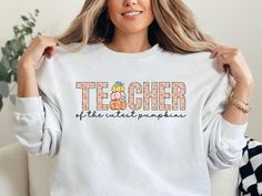 Are your students the cutest pumpkins? This cute fall sweatshirt is perfect for preschool, pre-K, and elementary teachers to wear this autumn. Plus, it would be so perfect for field trips to the pumpkin patch! ~Gildan brand shirts: medium-heavy cotton/polyester blend ~Unisex adult sizing: runs true to size, but size up if you'd like a more oversized fit. PRINT ~Our designs are printed using the highest quality professional direct-to-garment (DTG) process, meaning fabric-grade ink is printed directly onto the garment and blends with the fibers. This allows us to achieve a vintage-style look and a feel that is similar to screenprinting (which avoids the thick rubbery feeling of vinyl). ~All shirts are made to order. They will ship within one week from one of our printing partners. Please all Preschool Teacher Shirts, Fall School, Patch Shirt, Teacher Sweatshirt, Patches Shirt, Brand Shirts, Field Trips, Preschool Teacher, Screenprinting