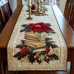 a christmas table runner with books and poinsettis on it, along with candles