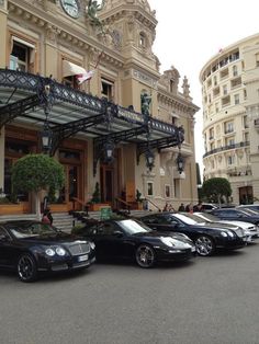 a group of cars parked in front of a building with a clock on the top