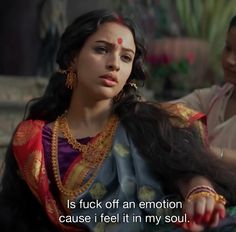 a woman with long black hair wearing a colorful sari and gold jewelry is sitting next to a man