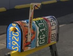 a colorful mailbox sitting on top of a yellow post