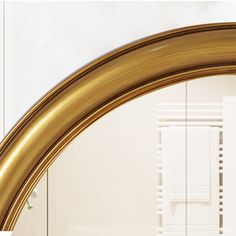 an oval mirror with gold trim in a bathroom