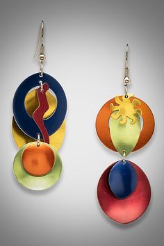 two colorful earrings are hanging from hooks on a gray background and one has an image of a woman