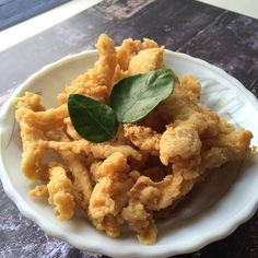 fried food on a white plate with a green leaf