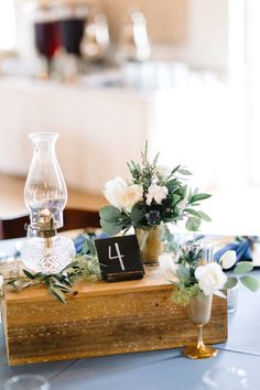 the table is set with flowers, candles and an old wooden box for numbers to be placed on