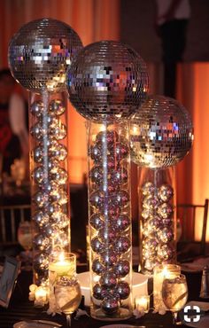 disco ball centerpieces with candles and place settings on a table at a party