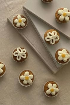 several cupcakes with white frosting and flowers on them sitting on a table