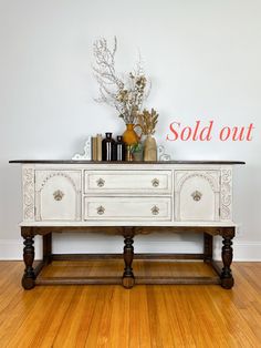 an old white dresser with some vases on top and the word sold out above it