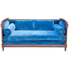 a blue velvet couch with wood trimmings on the arms and back, sitting in front of a white background