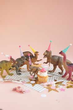 toy dinosaurs and cupcakes on a pink background