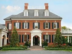 a large red brick house with black shutters and white trim on the front door