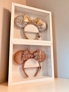 two minnie mouse ears are in a white box with gold sequins on them