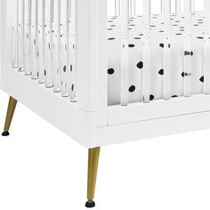 a white crib with black polka dots on the bottom and gold legs, against a white background