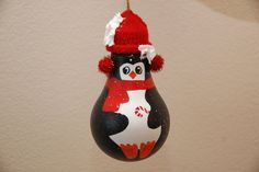 a penguin ornament hanging on a wall with a red hat and scarf around it's neck