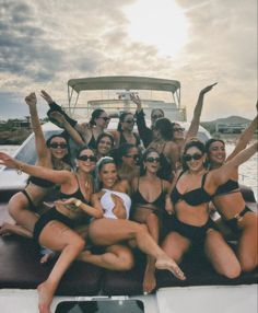 a group of women in bikinis on a boat posing for the camera with their arms up