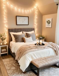 a bedroom decorated in neutrals and whites with lights on the wall above the bed