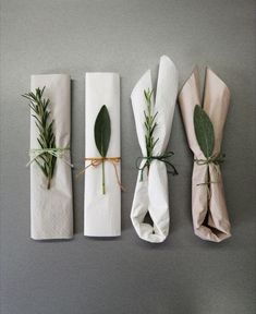 four napkins wrapped in white paper and tied with greenery