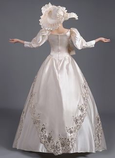 a woman in a white wedding dress with long sleeves and an elaborately designed skirt