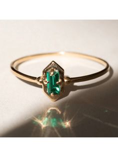 a gold ring with an emerald colored stone