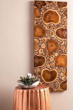 a wooden wall hanging on the side of a wall next to a potted plant