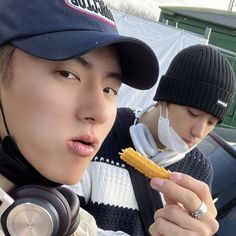 two young men wearing headphones and hats are eating cornflakes in the back of a car