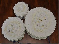 three white cakes sitting on top of a wooden table