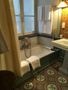 a bath tub sitting under a window next to a sink