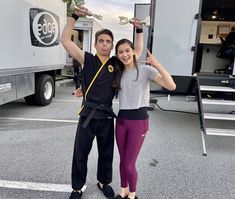 a man and woman pose for a photo in front of a food truck with their hands up