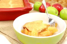 a bowl filled with apple cobbler next to a basket of apples and a fork