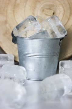 ice cubes are sitting in a bucket next to an old wooden slice of tree