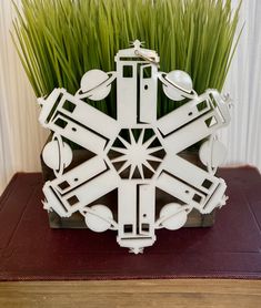 a white sculpture sitting on top of a wooden table next to green grass and a red book