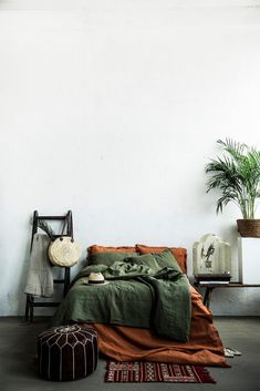 a bed sitting next to a plant in a room with white walls and flooring