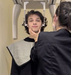 a man is looking at his reflection in the mirror as he stands next to a woman