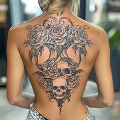 the back of a woman's body with roses and skulls tattooed on her chest