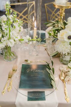 the table is set with white flowers and greenery for an elegant dinner or reception