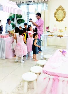 a group of people standing around a pink cake