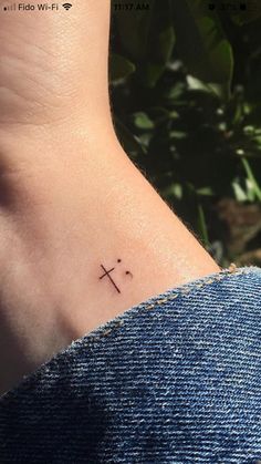 a small cross tattoo on the back of a woman's left side ribcage