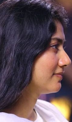 a close up of a person with long hair and wearing a white t - shirt