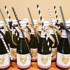 several bottles of champagne with black and white striped straws in them on a table