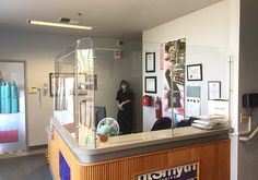 a person standing behind a counter in a room with pictures on the wall and posters above it