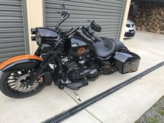 a black and orange motorcycle parked in front of a garage