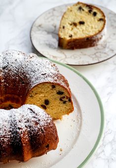 two bundt cakes sitting on top of plates covered in powdered sugar and sprinkled with chocolate chips