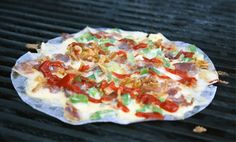 a pizza sitting on top of a grill covered in toppings