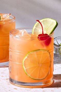 two glasses filled with drinks and garnished with limes